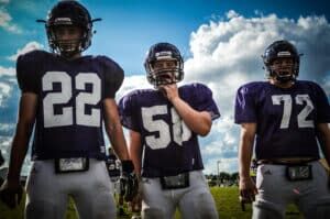 three football players wearing gorout devices at practice