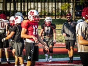 football team at practice with coach in background