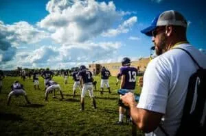 youth football coach at practice with whistle in mouth