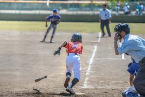 youth baseball batter running to first base