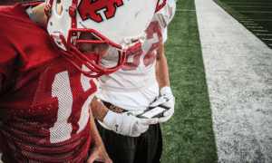 two football players looking at gorout device at practice