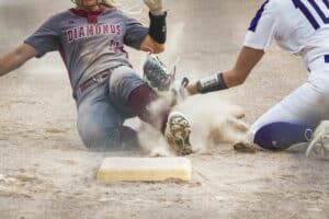 softball player getting tagged out sliding into second base