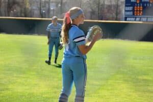 softball players warming up in outfield in between innings