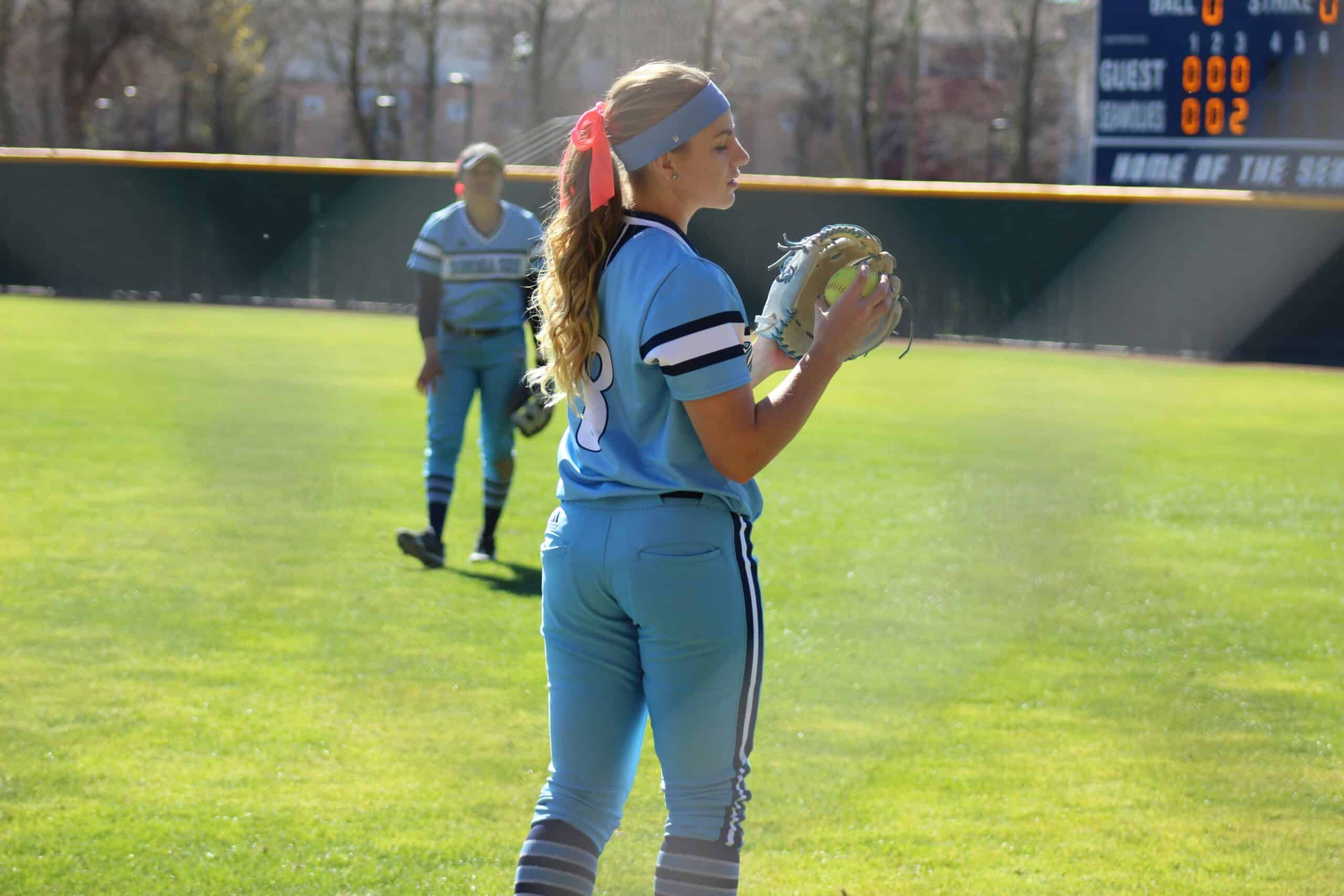 softball players warming up in outfield in between innings