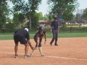 softball player high fives coach rounding third base