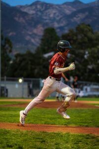 baseball player sprinting on field with mountain in background