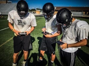 three football players using gorout device at practice