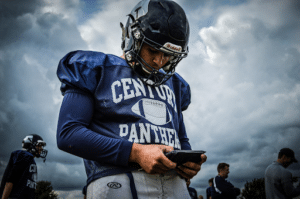 century panthers football player looking at device at practice