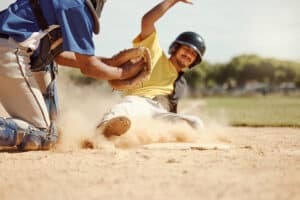 base runner sliding into home with catcher tagging