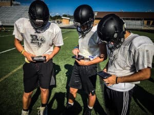 three football players using gorout device at practice