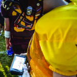 High school player looking at wearable play calling device