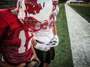 two football practice players looking at gorout device