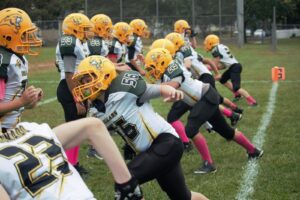 Youth football players running through warmup drills before a game