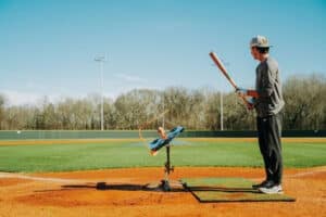 Baseball player using equipment to practice his swing on the field by himself