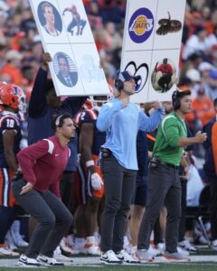 College play calling from the sideline with various cards and a decoy signaler disguising the play