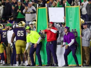 Decoy or "dummy" signal callers on a college football sideline wearing assorted colors which determine the correct sign