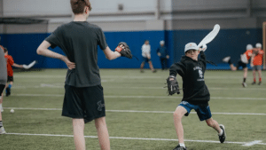 Youth baseball pitcher reaching back with a towel before snapping it on the target set by his throwing partner