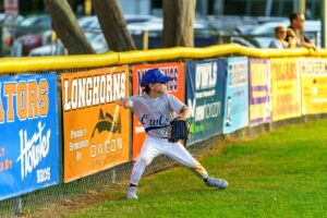 youth baseball outfielder throwing ball from the fence