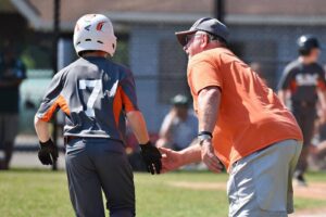 baseball coach high-fiving player rounding base