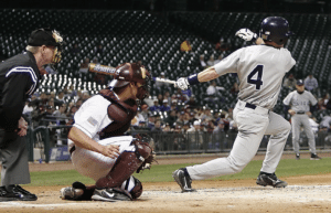 college baseball batter finishing swing while catcher and ump watch ball