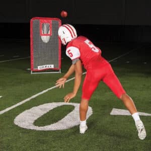 quarterback in full pads throwing to training net