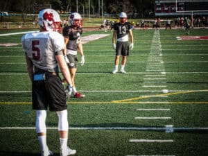 two defensive backs line up in formation against receiver at football practice
