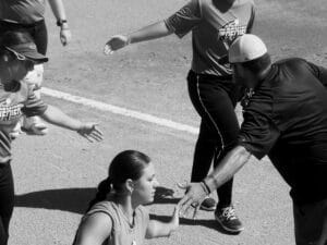 softball coach giving players high fives on field