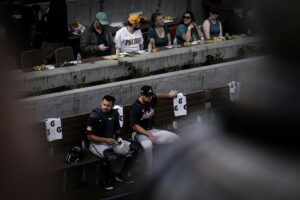 atlanta braves pitcher and catcher sit in bullpen with san diego fans in background